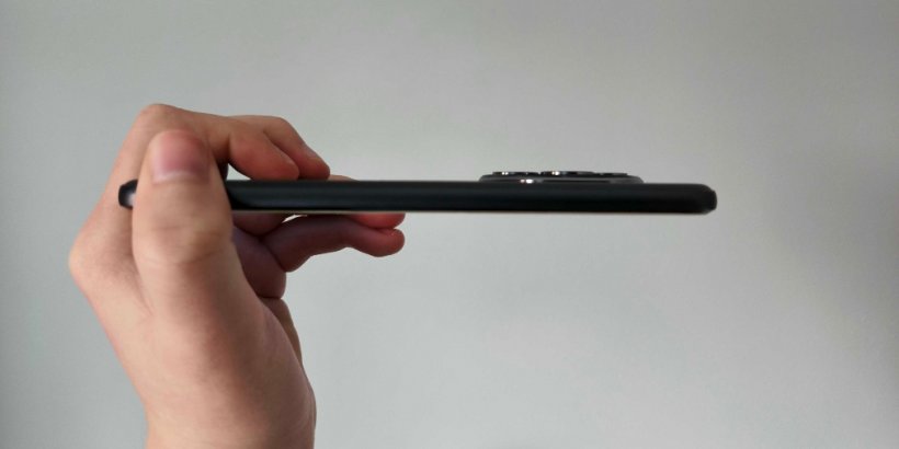 A side view of the Honor 400 Pro with a grey background and awkwardly placed fingers